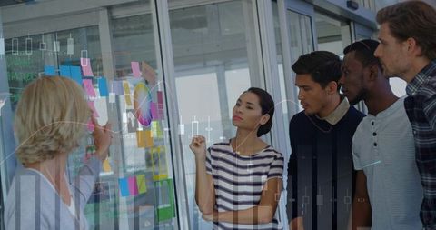 Collaborative team brainstorming at glass board using color wheel, sticky notes, charts