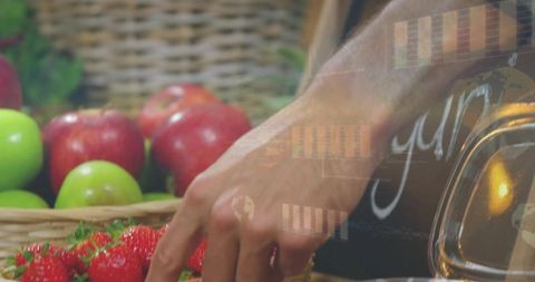 Reaching hand picking ripe strawberries at rustic market stall with wicker apples