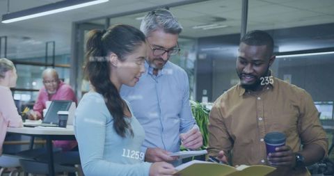 Diverse team collaborating around tablet and documents in modern open-plan office