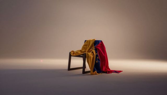 Wooden chair draping venezuelan flag under moody minimalist studio lighting