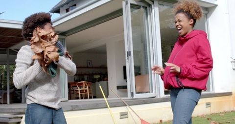 Joyful Mother and Son Play with Leaves in Garden