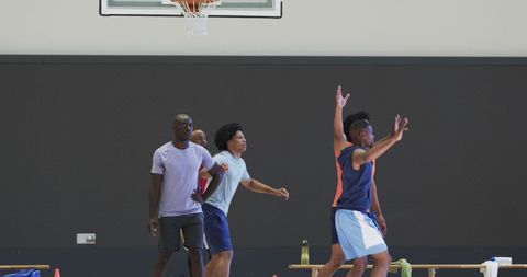 Diverse Group of Athletes Practicing Basketball Indoors with Coach