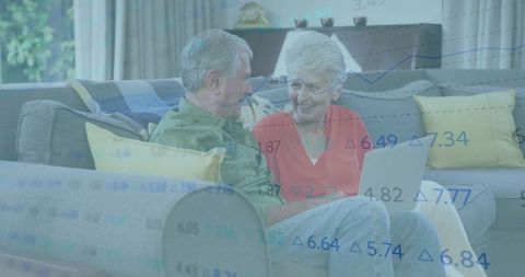 Senior Couple Operating Laptop Amidst Stock Market Data