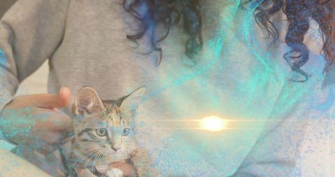 Woman cradling tabby kitten at home with soft teal light overlay, cozy cuddle moment
