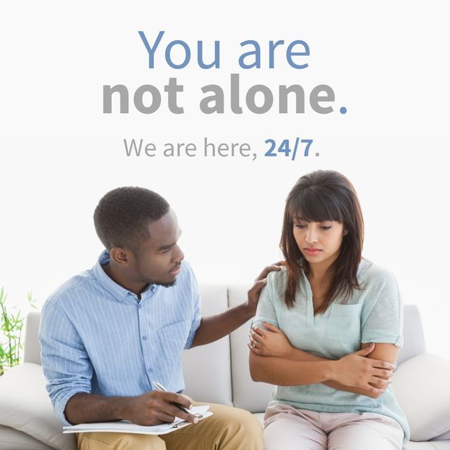 African American male counselor consoling a distressed young Asian woman. The text 'You are not alone. We are here, 24/7.' provides a sense of continuous support and mental health resources. Can be used in articles, campaigns, or websites related to mental health awareness, counseling services, support groups, or social services.