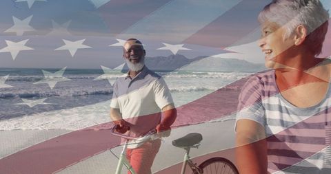 Happy Senior Biracial Couple Biking on Beach with American Flag Overlay