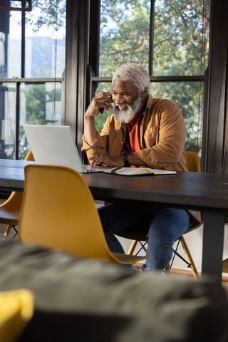 Senior african american man working remotely from home office smiling during phone call