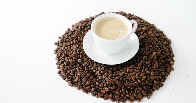 White ceramic cup filled with coffee placed in the center of a circular arrangement of fresh coffee beans on white surface. Ideal for showcasing coffee products, cafes, or articles on coffee culture, morning routines, and gourmet drinks.