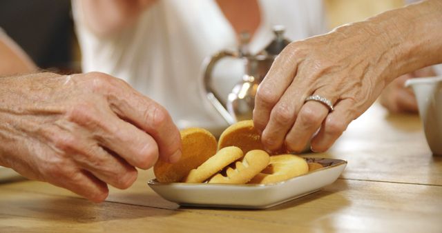 Senior Hands Reaching For Cookies on Wooden Table During Afternoon Tea - Download Free Stock Images Pikwizard.com