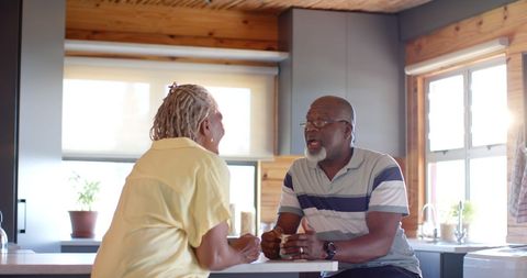 Senior African American Couple Chatting Over Coffee in Sunlit Kitchen