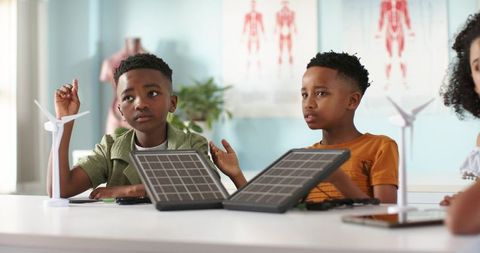 African american kids exploring renewable energy with solar panels and wind models