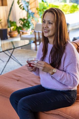 Relaxed senior asian woman enjoying tea on comfortable sofa