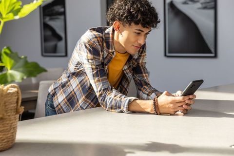 Young Man Relaxing at Kitchen Island Using Smartphone in Modern Space