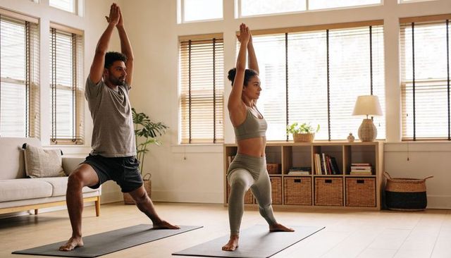 Couple practicing home yoga warrior lunge for strength, balance and mindful fitness