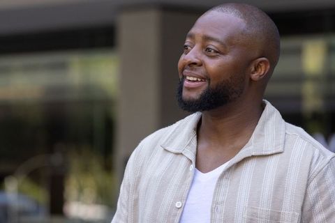 African man smiling outdoors in casual beige shirt urban portrait conveying warmth