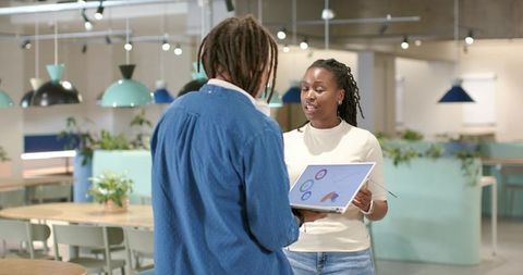 African American Colleagues Collaborating Pastel Open-Plan Coworking Space Presenting Data