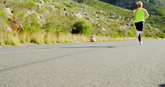 Caucasian woman jogging on a sunny road, with copy space. Outdoor exercise promotes a healthy lifestyle and mental well-being.