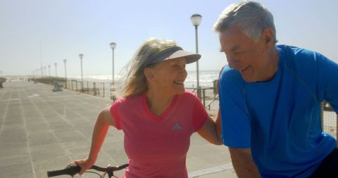 Active Senior Couple Enjoying Beach Promenade with Bicycle