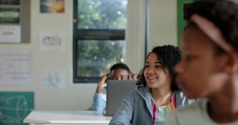 African American Students Smiling and Collaborating with Laptop and Headphones in Classroom