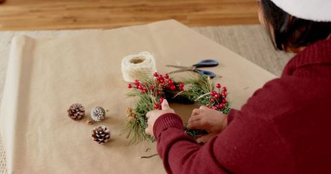Woman Crafting a Holiday Wreath with Pine and Berries