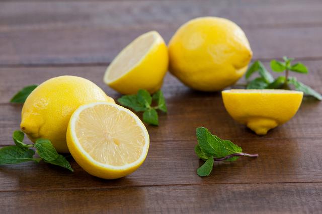 Fresh lemons and mint leaves placed on a wooden table. Ideal for use in recipes, healthy eating blogs, organic food promotions, summer refreshment advertisements, or as a vibrant background for culinary websites.