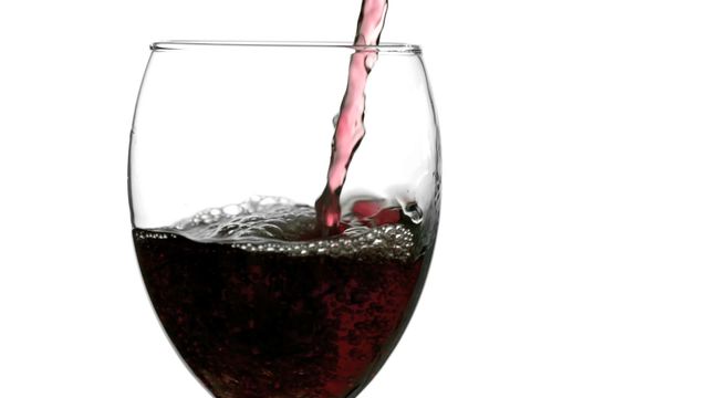 Slow motion capture of red wine being poured into a glass, centering on the splash and movement of the liquid. Perfect for use in advertising for wine brands, blog features about wine tasting, social media posts, and promotional materials for events related to wine and beverages. Also suitable for educational content illustrating fluid dynamics in a visually appealing way.