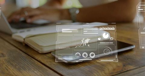 Tablet displaying holographic hud overlays resting on wooden table woman typing on laptop