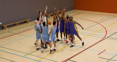 Diverse Basketball Teams Performing Tipoff in Gym
