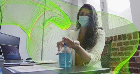 Professional woman using sanitizer at office desk ensuring health precautions