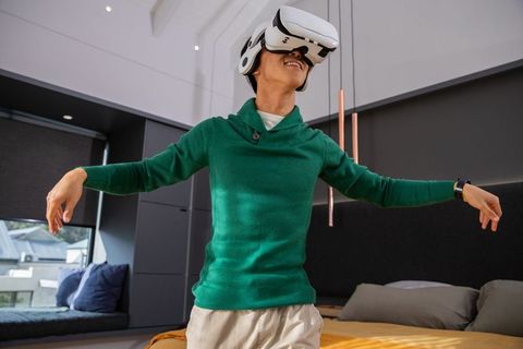 Young adult wearing vr headset exploring virtual world in modern bedroom interior