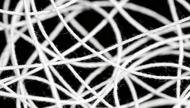 Tangled white cotton twine macro texture creating abstract fibrous web on black backdrop