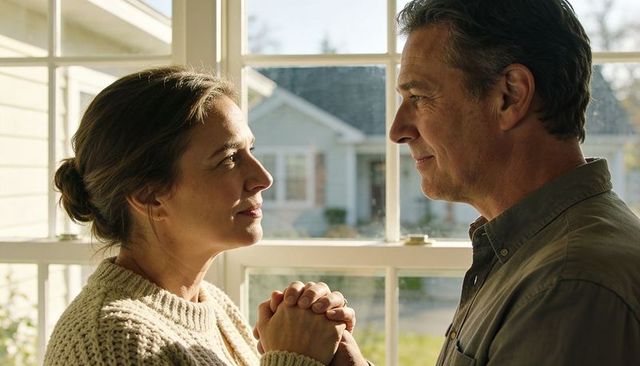 Mature couple holding hands by sunlit window sharing tender emotional connection