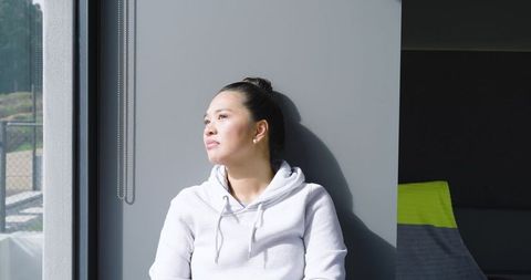 Asian woman relaxing near window with natural light
