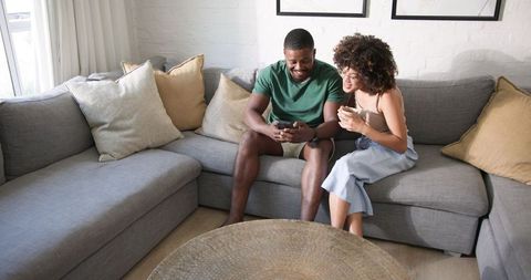 Couple Relaxing on Modern Sofa Sharing Smartphone Moments in Cozy Living Room