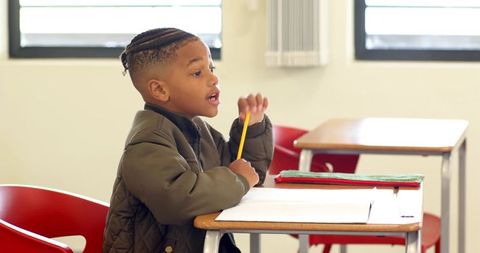 Focused Boy Writing in Classroom with Notebook