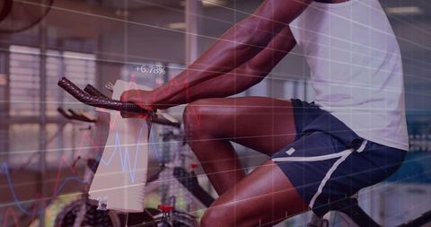 Male pedaling on stationary bike with performance analytics overlay in gym cardio studio