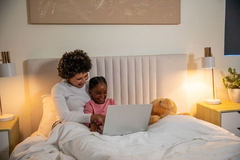 Mother and Daughter Bonding Over Laptop in Cozy Bedroom Setting