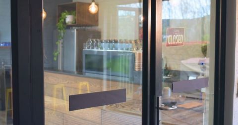 Closed cafe storefront showing glass door with closed sign reflecting wooden counter
