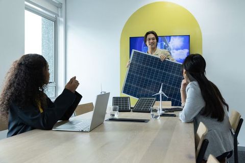 Diverse team presenting solar panel and model wind turbine in sustainable energy meeting