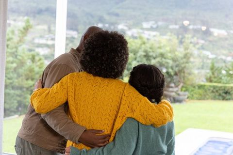 Embracing multiracial family in cozy patio hug overlooking backyard pool and hillside