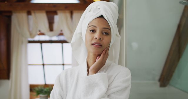 Portrait of biracial woman wearing bathrobe looking at camera. domestic life, spending quality free time relaxing at home.