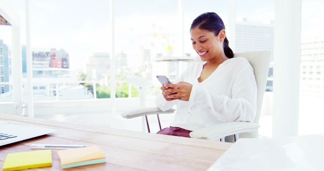 Young professional woman sitting in modern office working on smartphone - Download Free Stock Images Pikwizard.com