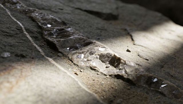 Sunlit quartz vein running across weathered bedrock with translucent crystals