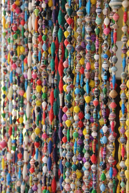Close-up view of colorful hanging bead decorations, showcasing vibrant colors and intricate patterns. Great for use in themes related to arts and crafts, handmade decor, festivals, parties, and celebrations. Ideal for showcasing skill in bead-making and adding a festive touch to content.