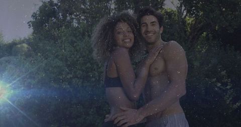 Joyful Mixed-Race Fitness Couple Embracing Outdoors with Sunflare
