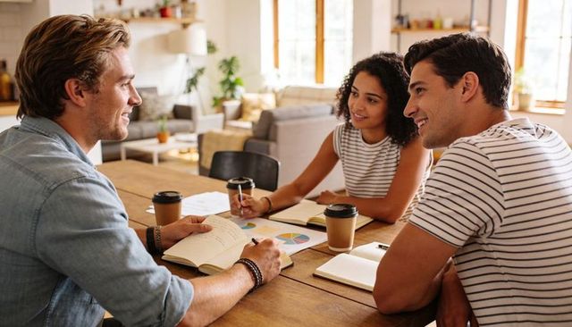 Young professionals collaborating over pie chart in sunlit modern living workspace
