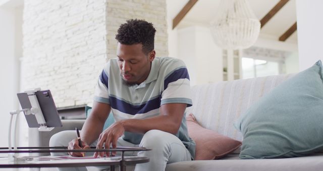 African american man working with tablet in living room. Spending quality time at home alone concept.