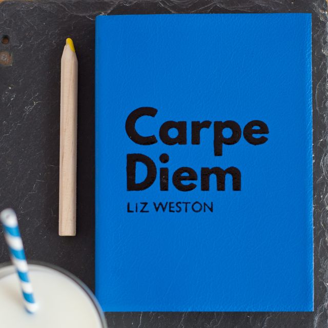 Blue journal with 'Carpe Diem' text on cover and pencil on slate background. Useful for themes like motivation, personal development, stationery use, or as an inspirational gift visual.