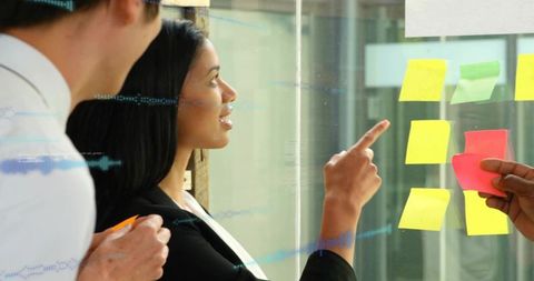 Team collaborating at glass wall using colorful sticky notes for agile planning session