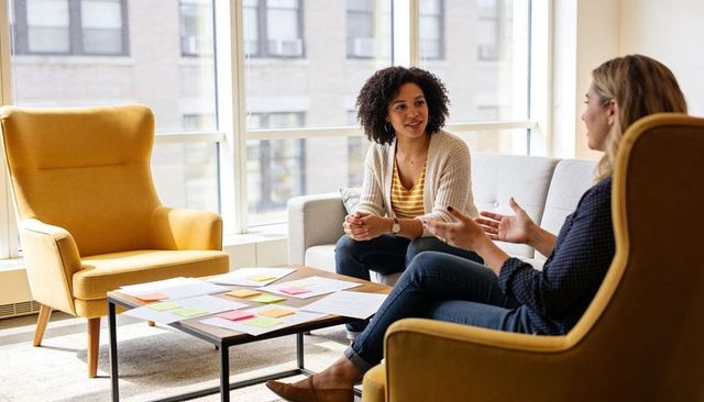 Two colleagues discussing plans and brainstorming in bright modern office lounge with sticky notes